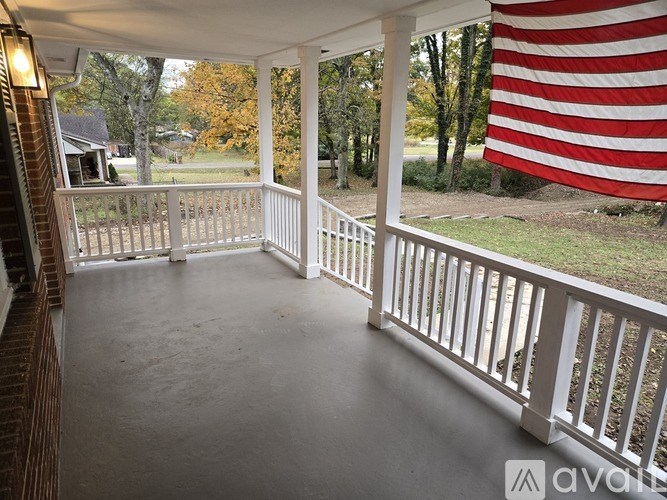 A porch with a white railing and a large American flag hanging on the wall.