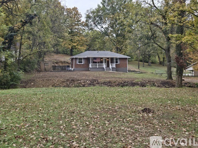 A house with a grey roof is surrounded by trees and grass.