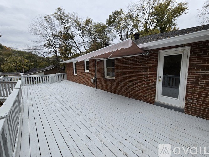 A wooden deck in front of a brick house with a white fence.