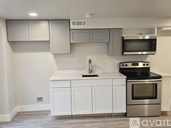 A modern kitchen with white cabinets and stainless steel appliances.