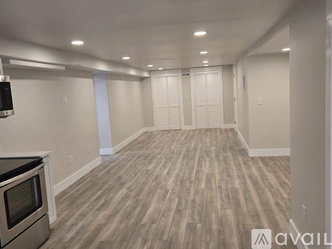 A spacious room with wooden flooring and a stainless steel oven.