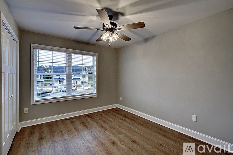 A room with a ceiling fan and a window overlooking a parking lot.
