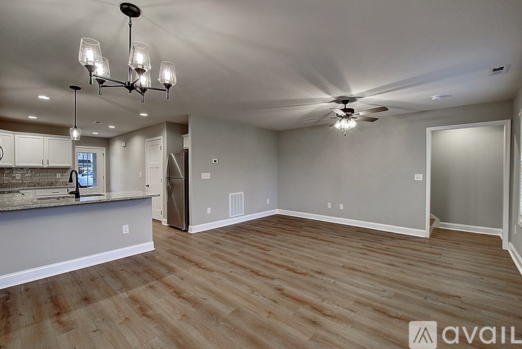 A spacious room with wooden flooring and a ceiling fan.