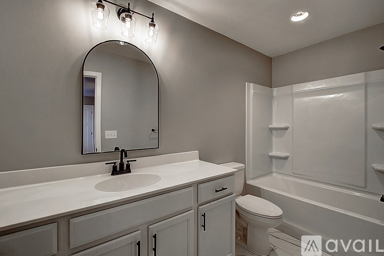 A bathroom with a sink, mirror, toilet, and bathtub.