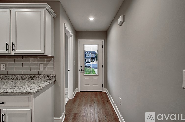 A kitchen with white cabinets and a view of a building outside the window.
