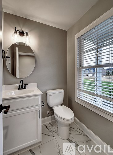 A bathroom with a toilet, sink, and mirror.
