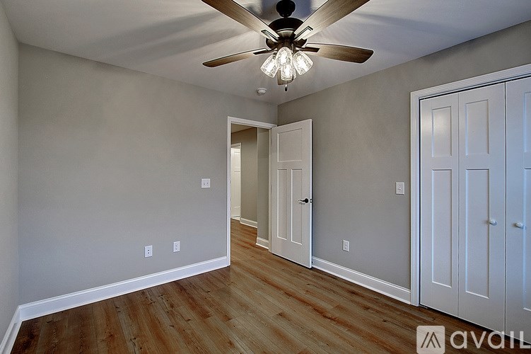 A room with a ceiling fan and wooden floors.