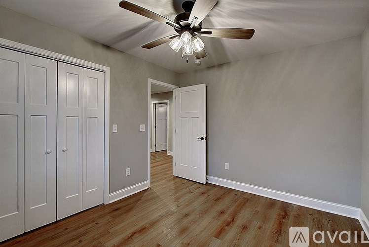A room with a ceiling fan and wooden floors.