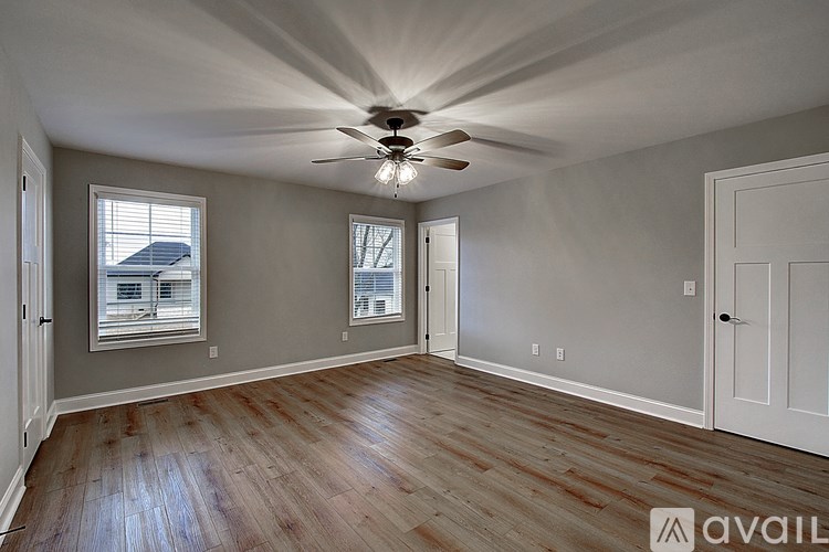 A room with a ceiling fan and wooden flooring.