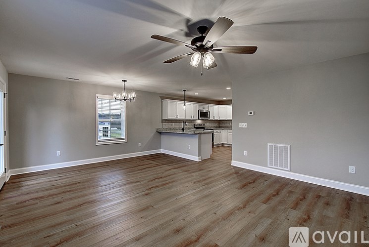 A spacious room with wooden flooring and a ceiling fan.