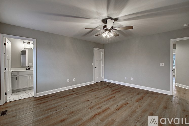 A spacious room with a ceiling fan and wooden flooring.