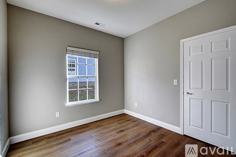 A room with a white door and a window with a view of the outside.