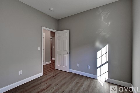 A room with a white door and wooden flooring.