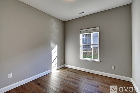 A room with a window and wooden flooring.