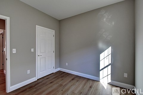 A room with a white door and a window letting in sunlight.