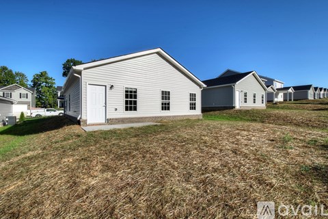 A house with a white door and windows is surrounded by a field.