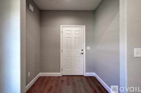 A room with a white door and wooden floor.