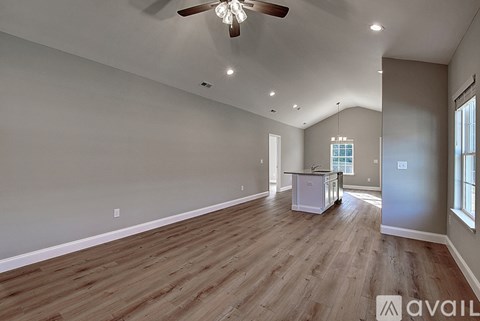 A spacious room with wooden flooring and a ceiling fan.