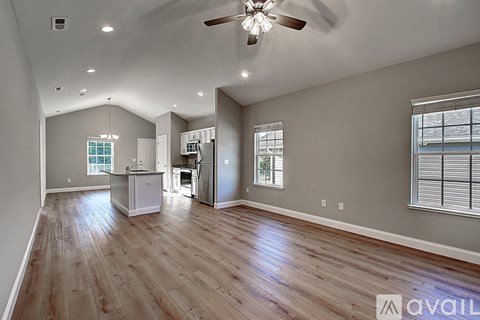 A spacious room with wood flooring and a ceiling fan.