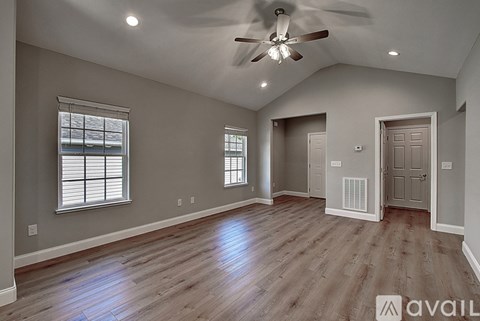 A spacious room with a ceiling fan and hardwood floors.
