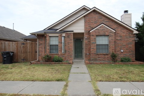 A brick house with a front yard and a trash can.