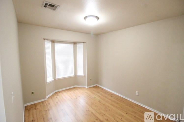 A room with wooden floors and a window with blinds.