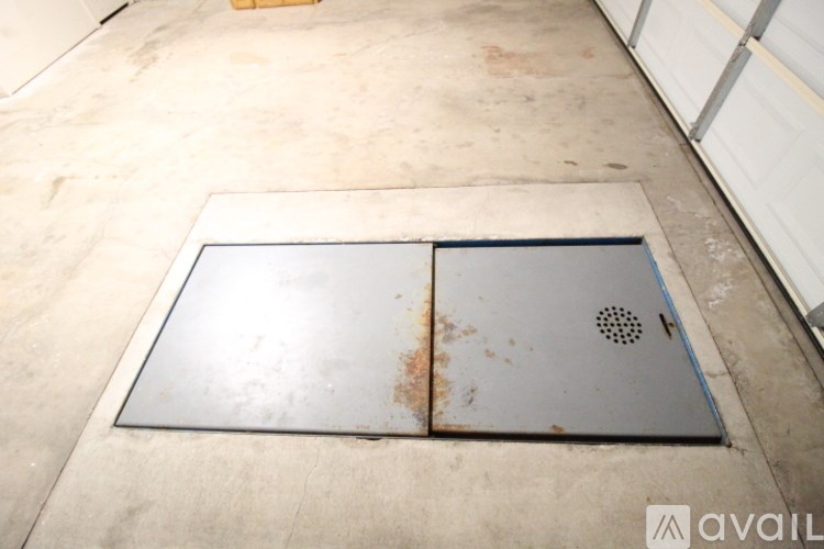A metal vent with a rusted surface is on a concrete floor.
