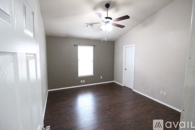 A room with a ceiling fan and wooden floors.