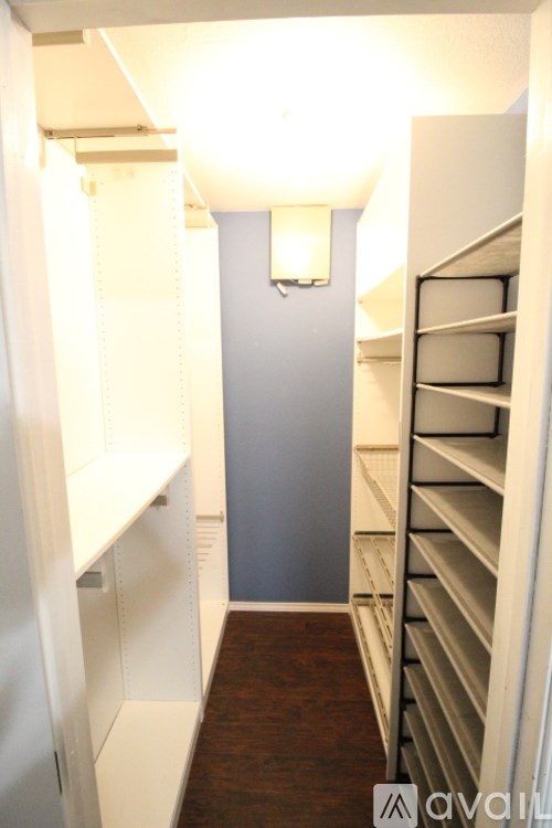 A hallway with white shelves on the side and a light on the wall.