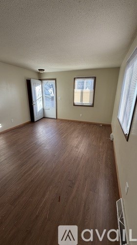 A room with wooden flooring and a window with blinds.