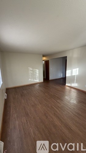 A room with wooden flooring and a doorway leading to another room.