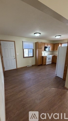 A kitchen area with wooden floors and a white refrigerator.