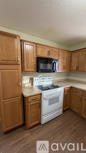 A kitchen with wooden cabinets and a white stove top oven.
