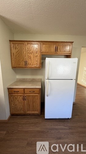 A kitchen with a white fridge and wooden cabinets.