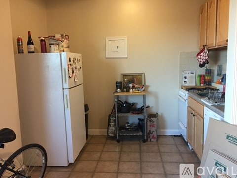 A kitchen with a white refrigerator, a small table with a few items on it, and a bicycle in the corner.