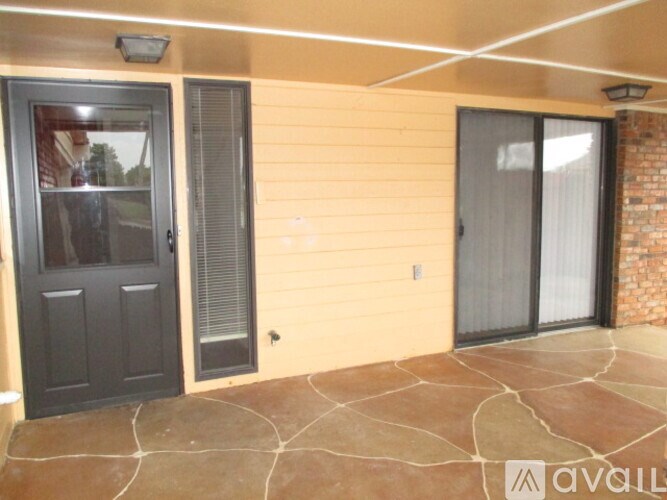 A patio area with a sliding glass door and a black door.