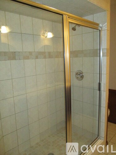 A shower stall with a gold frame and a glass door.