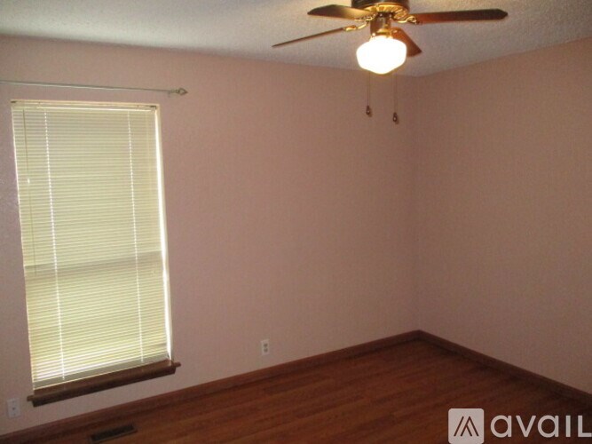 A room with a ceiling fan and a window with blinds.