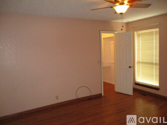 A room with a ceiling fan and a door leading to another room.