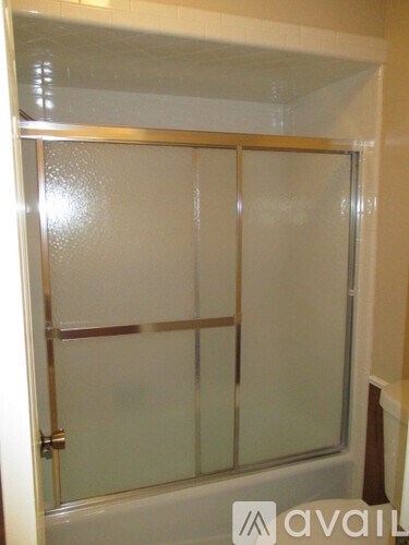 A glass shower door with a gold frame.