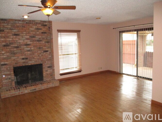 A room with a brick fireplace and wooden floors.