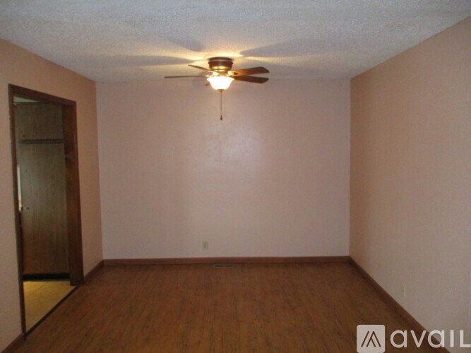 Empty room with a ceiling fan and wooden floor.