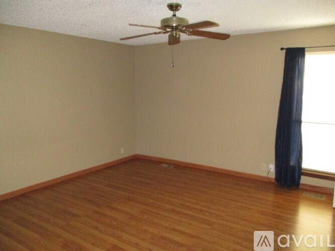 A room with a ceiling fan and wooden flooring.