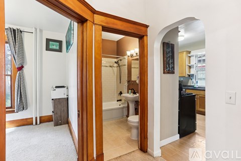 A bathroom with a toilet, sink, and mirror is visible through an open door.