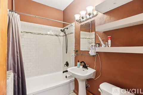 A bathroom with a brown wall and white fixtures.