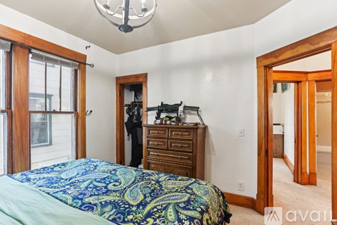 A bedroom with a bed, dresser, and a chandelier.