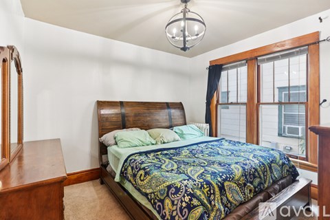 A bedroom with a bed, a dresser, and a window.