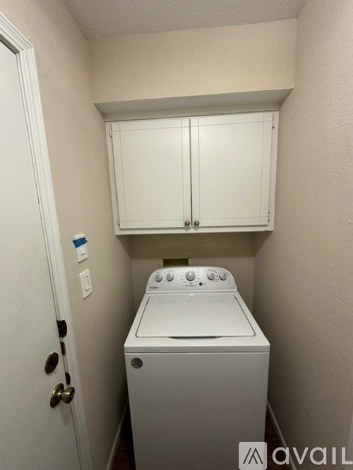 A small white washing machine sits in a laundry room.