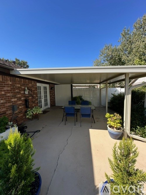 A patio with a table and chairs under a roof.