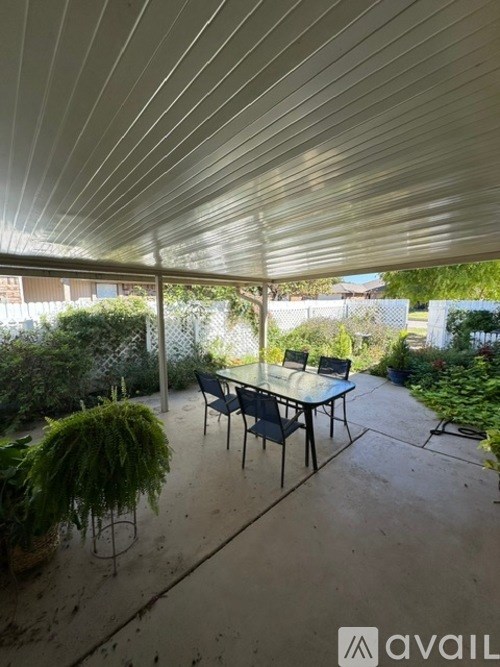 A patio with a table and chairs under a roof.